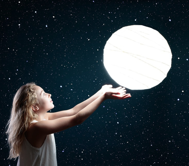 Photo altered to look like a young girl is holding the moon